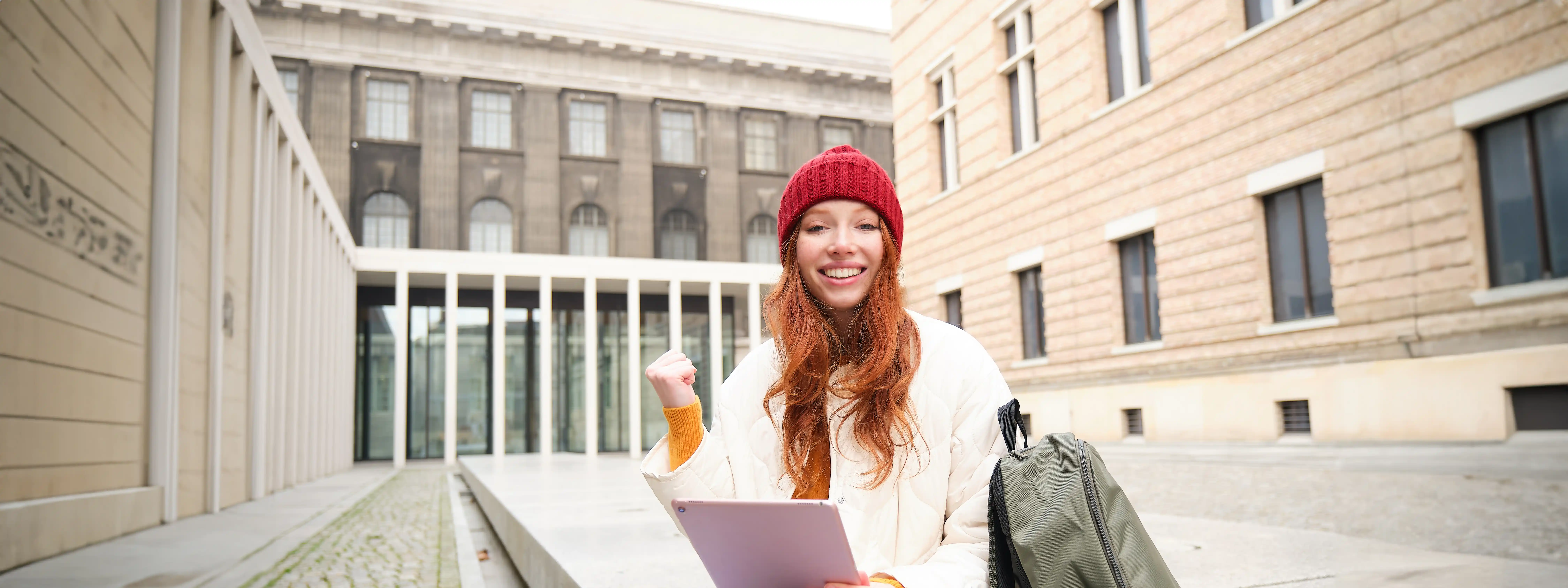 College student filling out FAFSA form on laptop with campus background